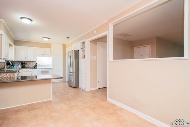 kitchen with under cabinet range hood, tasteful backsplash, dark countertops, freestanding refrigerator, and white electric stove