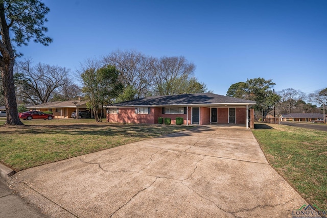 ranch-style house featuring an attached carport, concrete driveway, and a front lawn