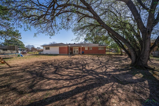 rear view of property featuring a trampoline and fence