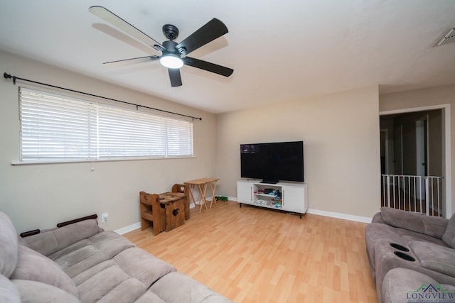 living room with visible vents, baseboards, light wood-style floors, and a ceiling fan