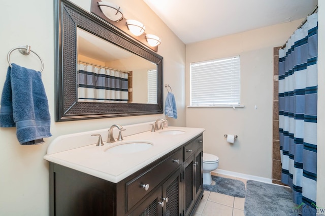 full bath with tile patterned floors, double vanity, toilet, and a sink