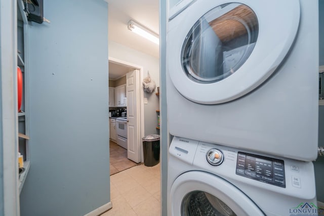 clothes washing area featuring light tile patterned floors, laundry area, and stacked washer / drying machine