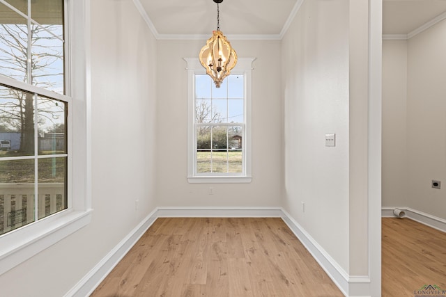 unfurnished dining area featuring light hardwood / wood-style flooring, ornamental molding, and a chandelier