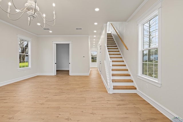 unfurnished living room with ornamental molding, a healthy amount of sunlight, a chandelier, and light hardwood / wood-style floors