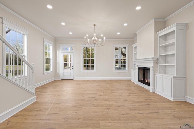 unfurnished living room featuring a notable chandelier, built in features, ornamental molding, and light hardwood / wood-style floors