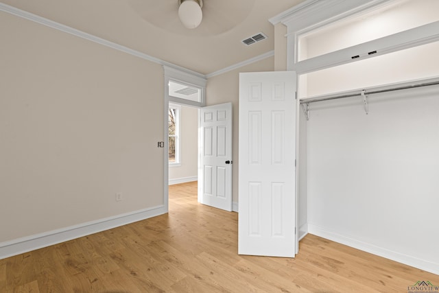 unfurnished bedroom with crown molding, a closet, ceiling fan, and light wood-type flooring