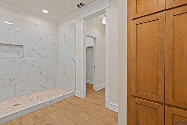 bathroom with hardwood / wood-style flooring, ornamental molding, and tiled shower