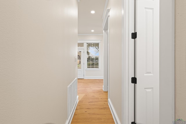 hallway featuring crown molding and light hardwood / wood-style flooring