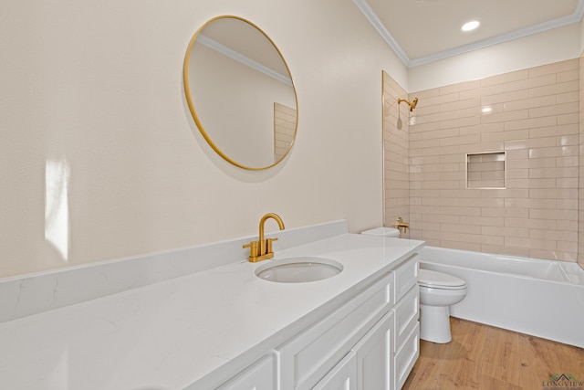 full bathroom featuring tiled shower / bath combo, vanity, wood-type flooring, ornamental molding, and toilet