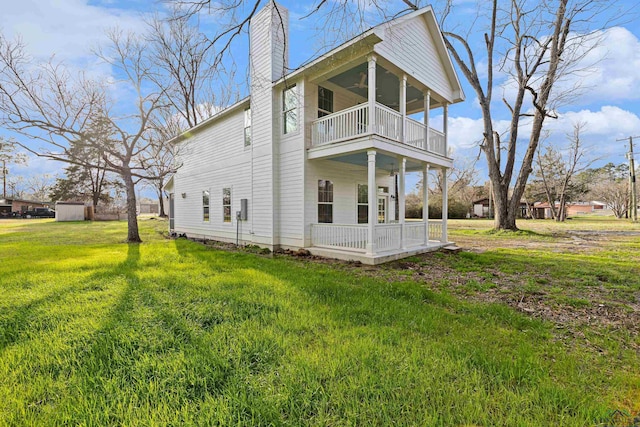 rear view of house with a balcony, a yard, covered porch, and ceiling fan