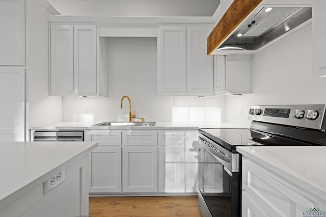 kitchen featuring stainless steel range with electric stovetop, white cabinets, and premium range hood