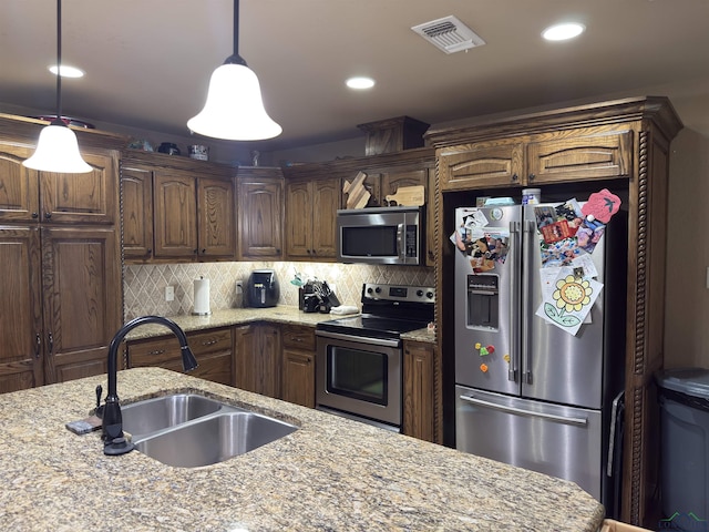 kitchen with visible vents, pendant lighting, a sink, backsplash, and stainless steel appliances