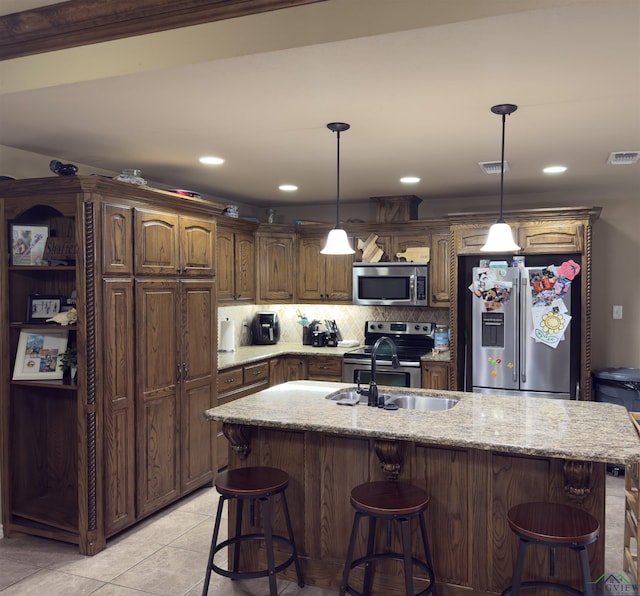 kitchen with light stone counters, visible vents, stainless steel appliances, a kitchen breakfast bar, and backsplash