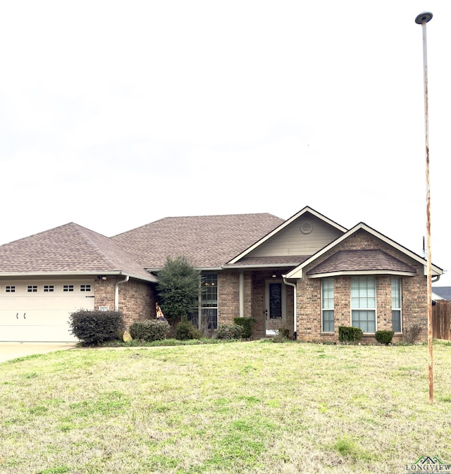 single story home featuring driveway, a front yard, a shingled roof, a garage, and brick siding