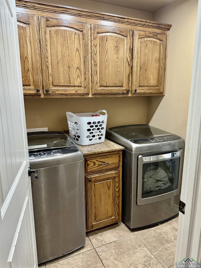 clothes washing area with washer and dryer, cabinet space, and light tile patterned floors