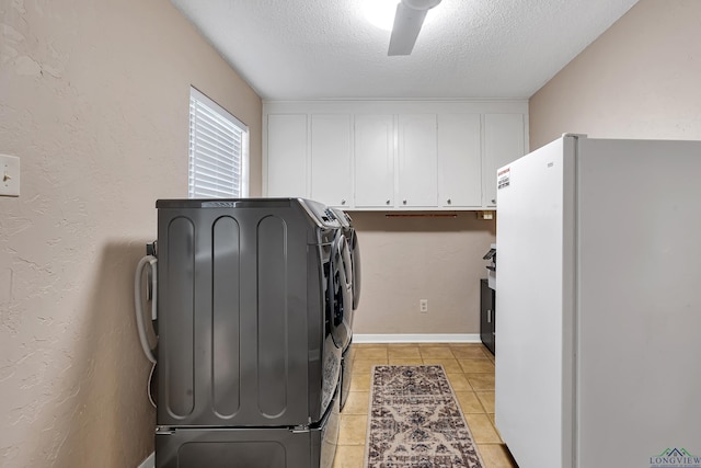 laundry area with washer and clothes dryer, cabinets, light tile patterned floors, and a textured ceiling