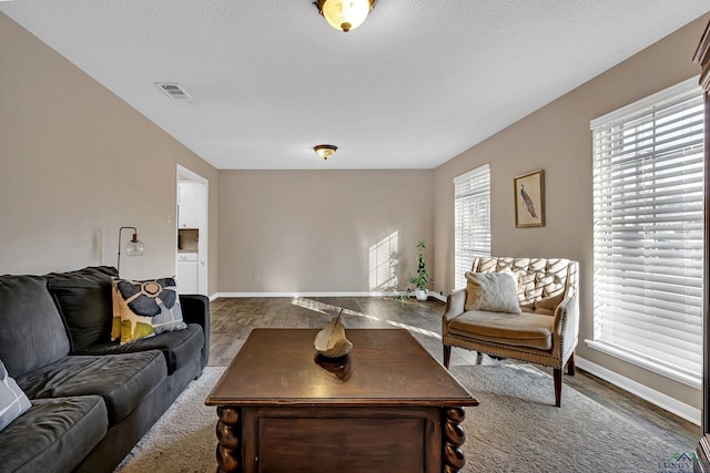 living room with a textured ceiling, a healthy amount of sunlight, and dark hardwood / wood-style floors