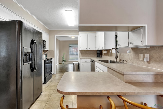 kitchen featuring sink, a textured ceiling, a breakfast bar area, white cabinets, and black appliances