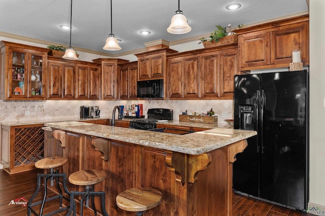 kitchen with black appliances, crown molding, hanging light fixtures, dark hardwood / wood-style floors, and light stone countertops