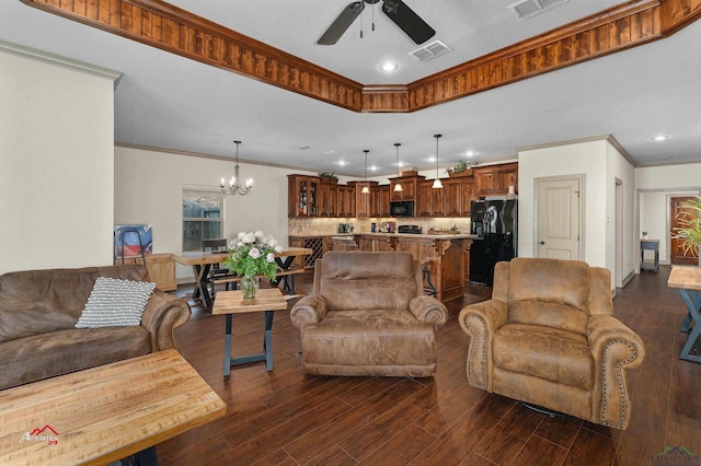 living room featuring crown molding, dark wood-type flooring, and ceiling fan with notable chandelier