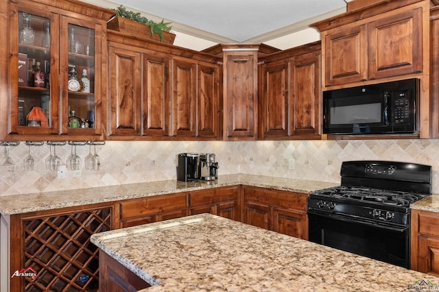 kitchen with light stone countertops, decorative backsplash, and black appliances