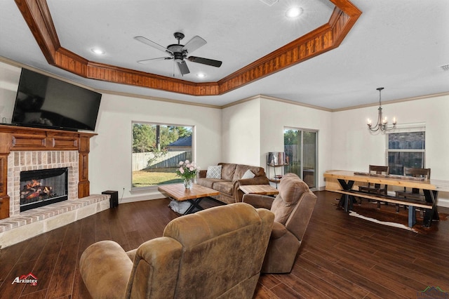 living room with a raised ceiling, a fireplace, ceiling fan with notable chandelier, and dark hardwood / wood-style floors