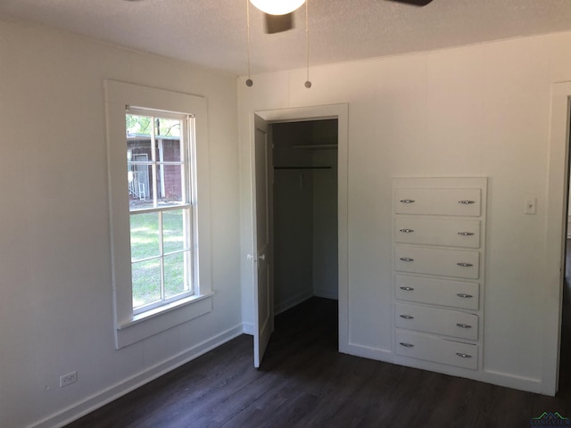 602 Premier Rd, Longview, TX 75604 - unfurnished bedroom with dark wood finished floors, multiple windows, a spacious closet, a textured ceiling, and a closet