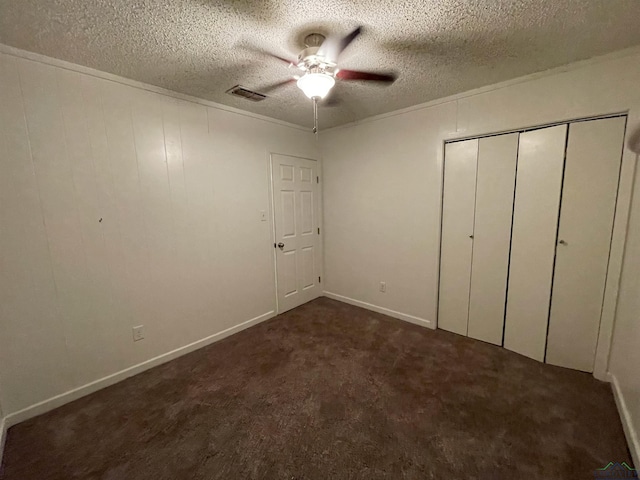 unfurnished bedroom with dark colored carpet, a textured ceiling, a closet, and ceiling fan