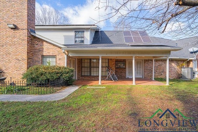 view of front of house with solar panels, cooling unit, and a front lawn