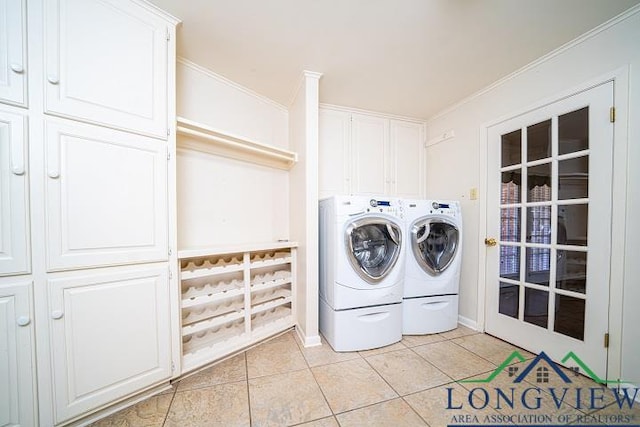 clothes washing area with cabinets, crown molding, light tile patterned floors, and washer and dryer