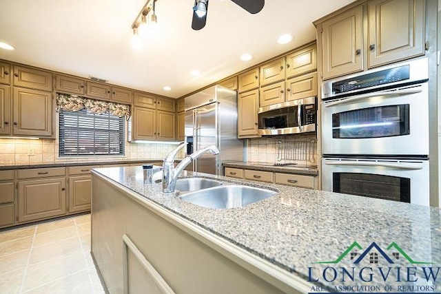 kitchen featuring sink, stainless steel appliances, light stone counters, decorative backsplash, and light tile patterned floors