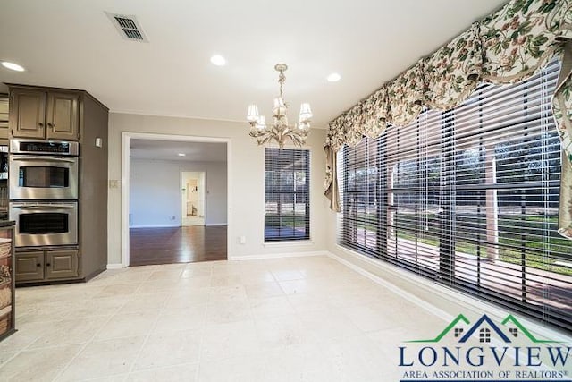 interior space with light tile patterned floors, stainless steel double oven, dark brown cabinetry, and a notable chandelier