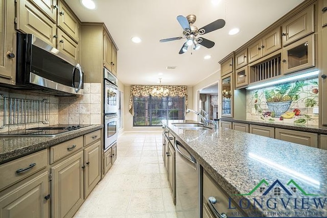 kitchen featuring appliances with stainless steel finishes, tasteful backsplash, dark stone countertops, and sink