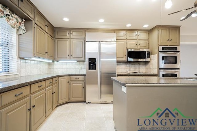 kitchen featuring stone counters, ceiling fan, stainless steel appliances, tasteful backsplash, and light tile patterned floors