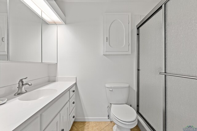 bathroom with tile patterned flooring, vanity, toilet, and walk in shower