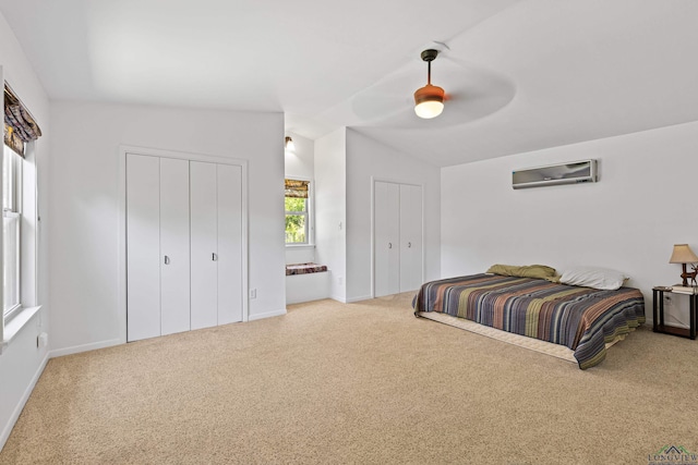 carpeted bedroom featuring ceiling fan, lofted ceiling, a wall mounted AC, and two closets