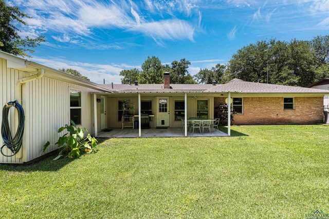 rear view of house with a patio area and a lawn