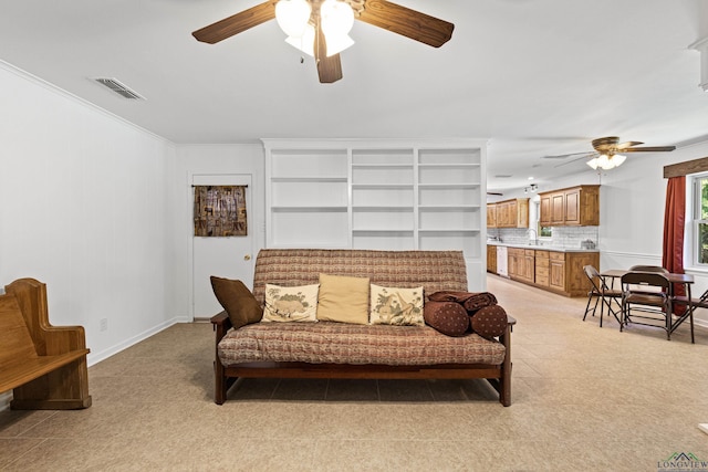 living room featuring ceiling fan, ornamental molding, and sink