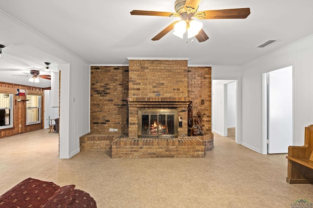 living room with wood walls, a fireplace, ceiling fan, and crown molding