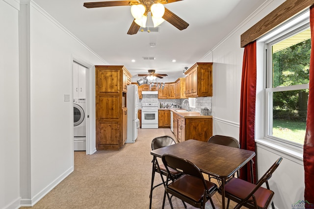 dining space featuring ceiling fan, washer / dryer, ornamental molding, and sink