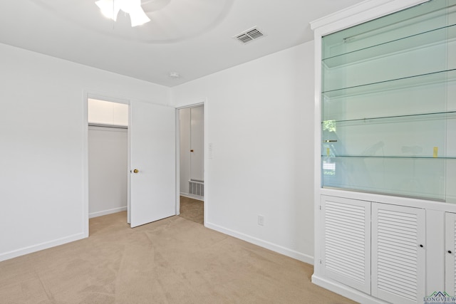 unfurnished bedroom with ceiling fan, light colored carpet, and a closet