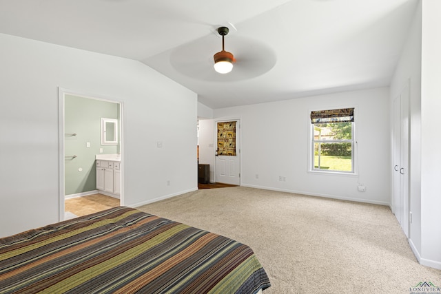 unfurnished bedroom featuring vaulted ceiling, light colored carpet, ensuite bath, and ceiling fan