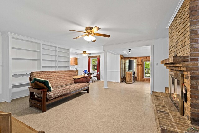 living room featuring ceiling fan, a fireplace, a healthy amount of sunlight, and wooden walls