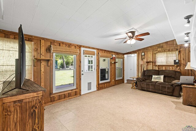 living room with vaulted ceiling, ceiling fan, and wooden walls