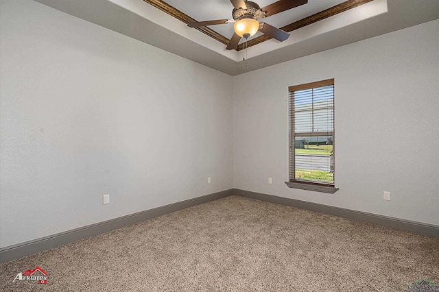 carpeted empty room featuring ceiling fan and a raised ceiling