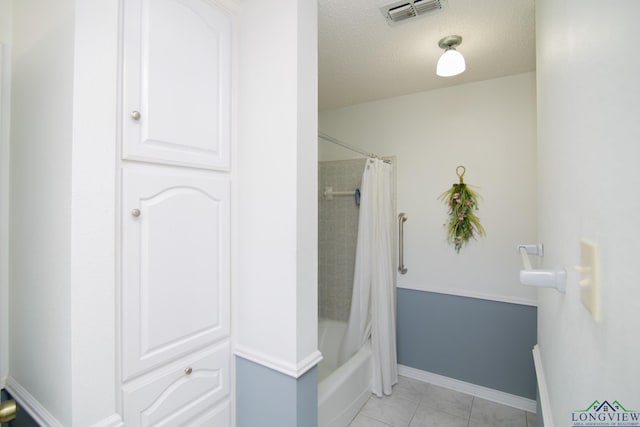 bathroom with tile patterned flooring, shower / bath combo with shower curtain, and a textured ceiling