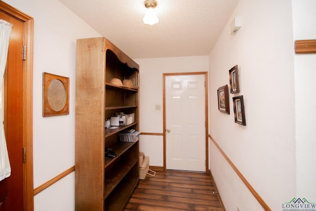 corridor with dark hardwood / wood-style floors and a textured ceiling