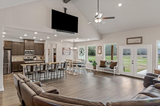 living room with ceiling fan with notable chandelier, hardwood / wood-style floors, french doors, high vaulted ceiling, and beam ceiling