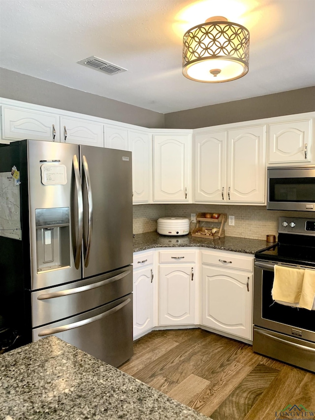 4401 Leland St, Marshall, TX 75672 - kitchen with appliances with stainless steel finishes, dark stone countertops, white cabinetry, and wood finished floors