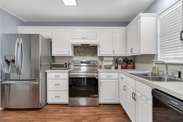 kitchen with appliances with stainless steel finishes, a sink, under cabinet range hood, white cabinetry, and light countertops